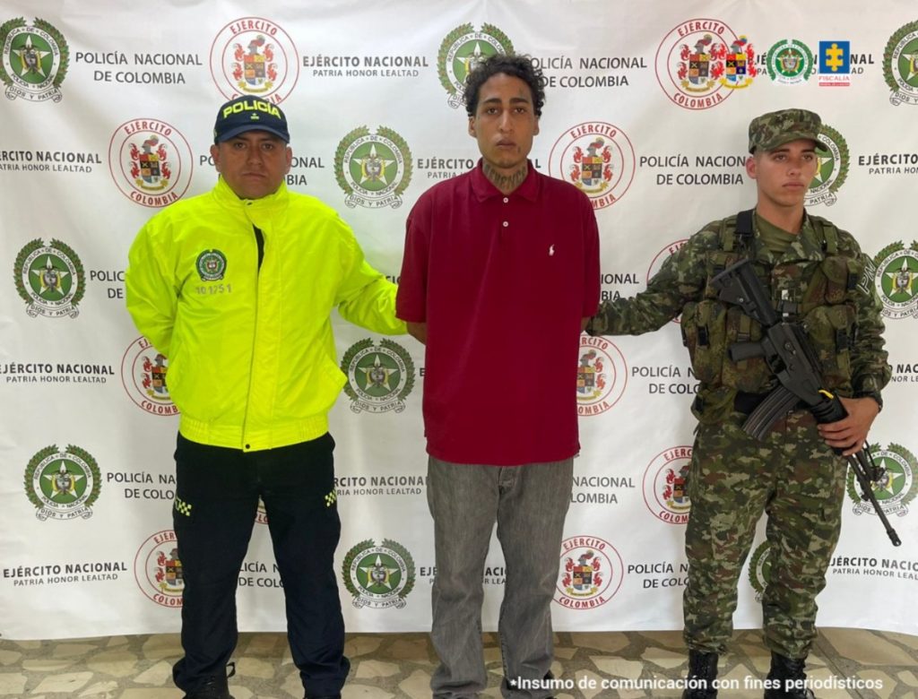 En la imagen aparece el investigado en medio de un policía y un soldado.