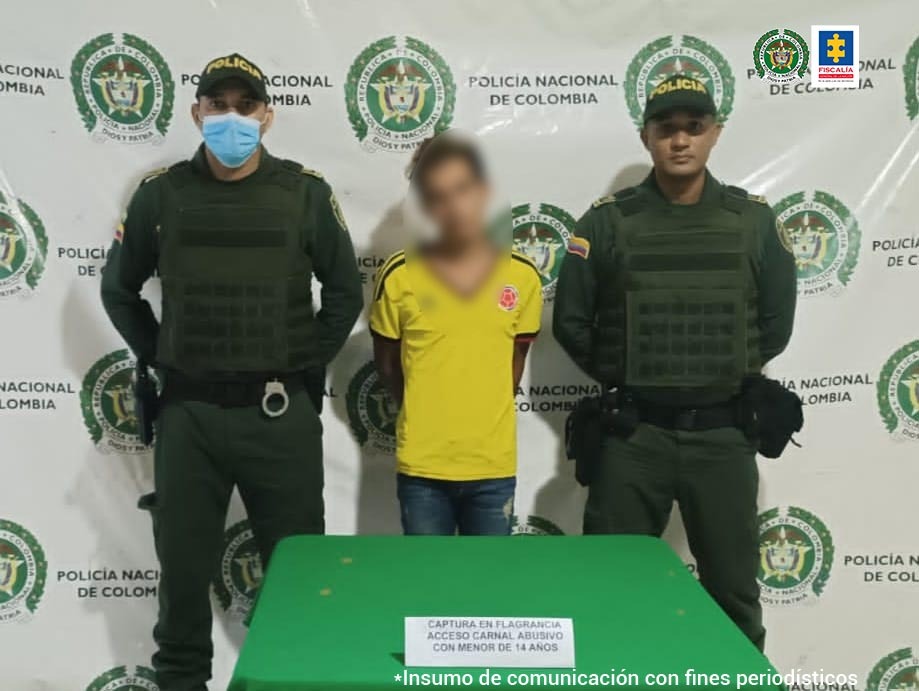 En la fotografía aparece un hombre capturado, junto a personal de la Policía Nacional. En la parte posterior de la imagen se ve un banner con logos de la misma entidad.
