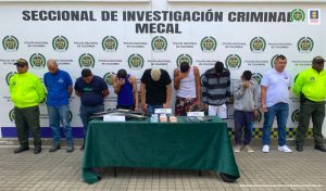 En la fotografía se aprecia a los presuntos integrantes de ‘Los Remoto’. Siete de ellos se encuentran con la cabeza agachada. En los extremos hay uniformados de la Policía Nacional. Delante de ellos hay una mesa con mantel verde y sobre ella hay teléfonos celulares, partes de motocicletas y cajas con teléfonos móviles. Asimismo, hay tres letreros que dicen: ‘Partes de motocicletas’, ‘Celular incautado’, ‘celular recuperado’. Detrás de ellos hay un pendón institucional de la Policía.