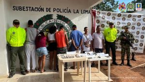 En la fotografía aparecen varias personas capturadas, acompañada de dos uniformados de la Policía y Ejército Nacional. En la parte posterior dos banners con el logos de la entidad.