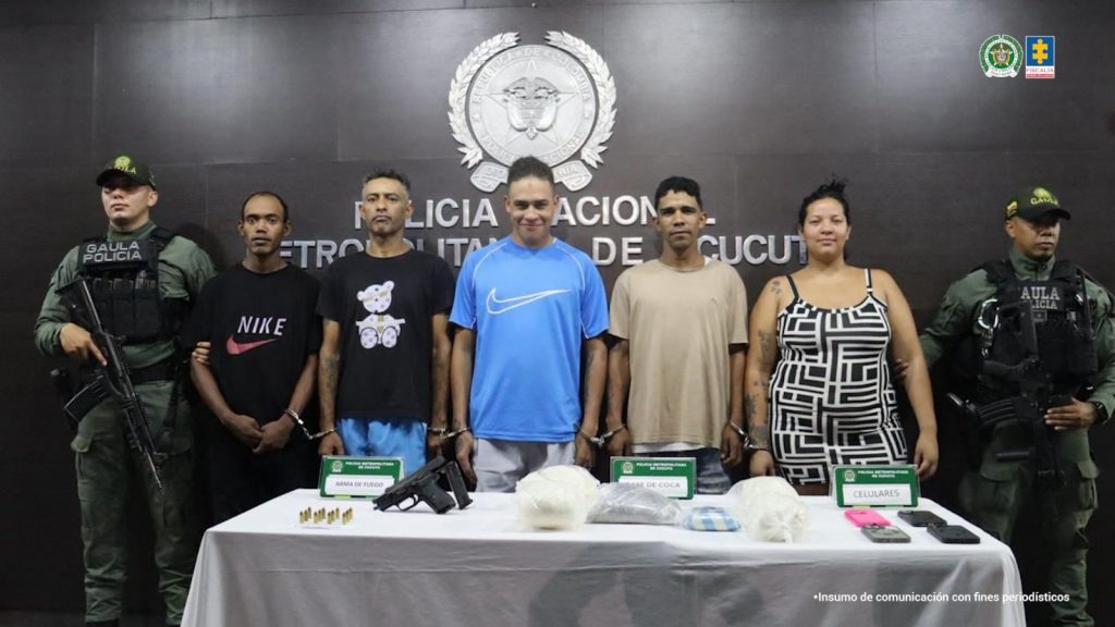 Se visualiza a los cinco capturados junto a uniformados del Gaula de la Policía Nacional. Frente a ellos una mesa con los elementos incautados. Detrás de ellos el banner que identifica a la Policía Nacional.