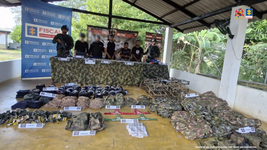 En la imagen aparecen dos hombres y una mujer acompañadas de un servidores del CTI y el Ejército Nacional, Al frente hay una mesa con abundantes munición para fusil.