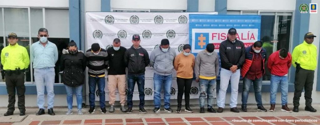 En la foto aparecen los presuntos implicados en la falsificación de licencias de conducción, en Popayán (Cauca). A los extremos de los hoy imputados hay uniformados de la Policía Nacional. Detrás de ellos hay dos pendones institucionales de la Policía y la Fiscalía.