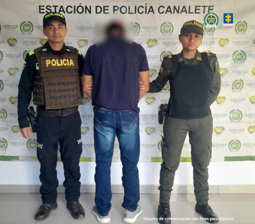 En la imagen aparece una persona de suéter azul entre dos uniformados de la Policía.