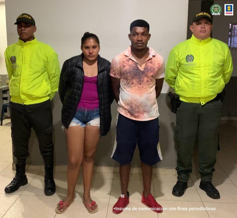 En la imagen se ven dos personas, hombre y mujer, entre uniformados de la Policía.