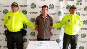 En la imagen aparece el procesado, con camiseta de color negro con blanco, en medio de dos uniformados de la Policìa Nacional