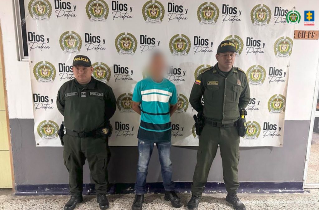 En la imagen aparece una persona de suéter verde entre dos uniformados de la Policía.
