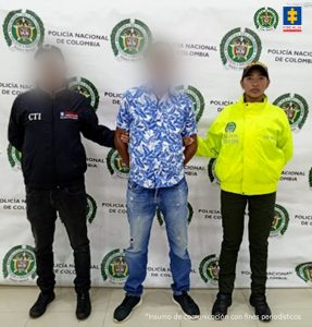 En la imagen aparece una persona como camisa azul con blanco, entre dos uniformados de la Policía y el CTI.