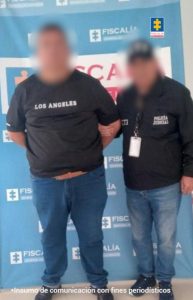 En la imagen aparece una persona de suéter negro junto a un uniformado de la Policía. 