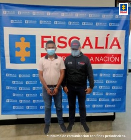 En la fotografía aparece el capturado junto a un investigador del CTI. En la parte posterior se observa el banner que identifica a la Fiscalía General de la Nación.