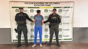 Se observa al capturado junto a dos uniformados de la Policía Nacional. Detrás de ellos el banner que identifica a la Policía Nacional.