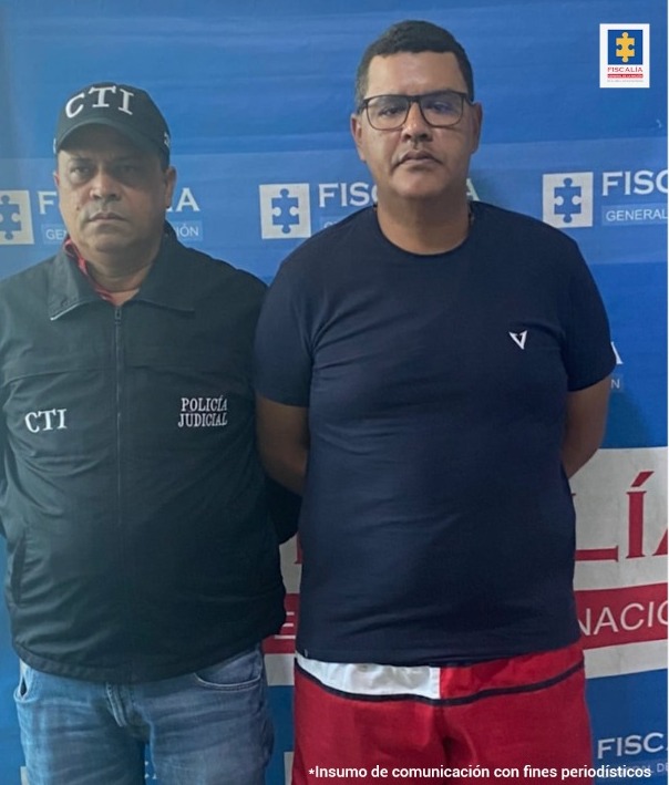 En la fotografía aparece un hombre capturado, acompañado de un servidor del CTI. En la parte posterior un banner con logos de la Fiscalía General de la Nación.
