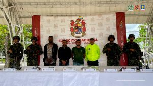 En la imagen están los 3 procesados con 4 servidores del Ejército y uno de la Policía Nacional a los lados y adelante una mesa con las armas, municiones y aparatos de comunicación incautados.