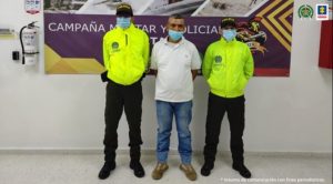 En la fotografía se aprecia al capturado junto a dos uniformados de la Policía Nacional, en la parte posterior un banner de la campaña militar y policial Esparta