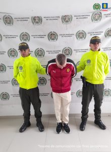 en la imagen se ve una persona detenida bajo custodia de dos uniformados de la Policía Nacional.