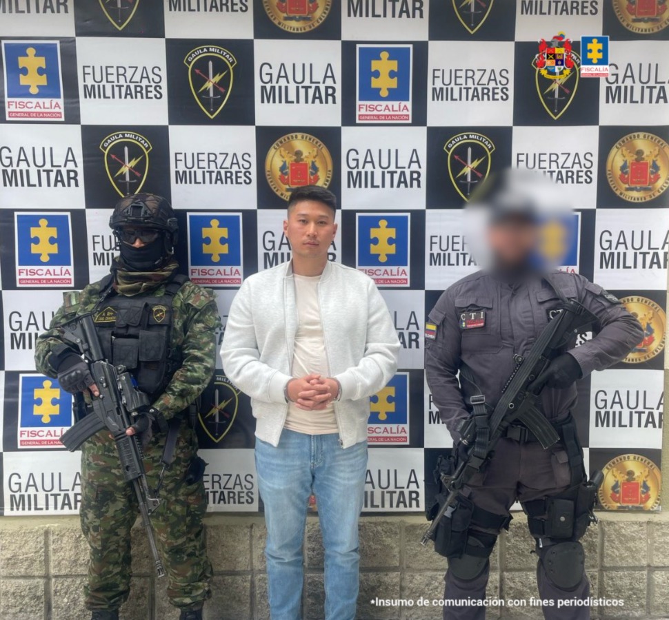 En la foto está el hombre en medio de un funcionario del CTI y otro del Ejército Nacional, y  un pendón  atrás con los logos de la Fiscalía, el ejército y el Gaula militar