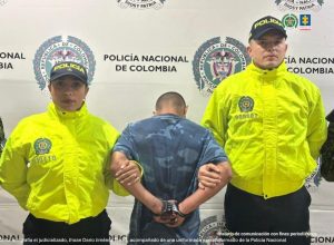En el registro fotográfico, el judicializado, Jhoan Darío Jiménez Torres, acompañado por una uniformada y un uniformado de la Policía Nacional.