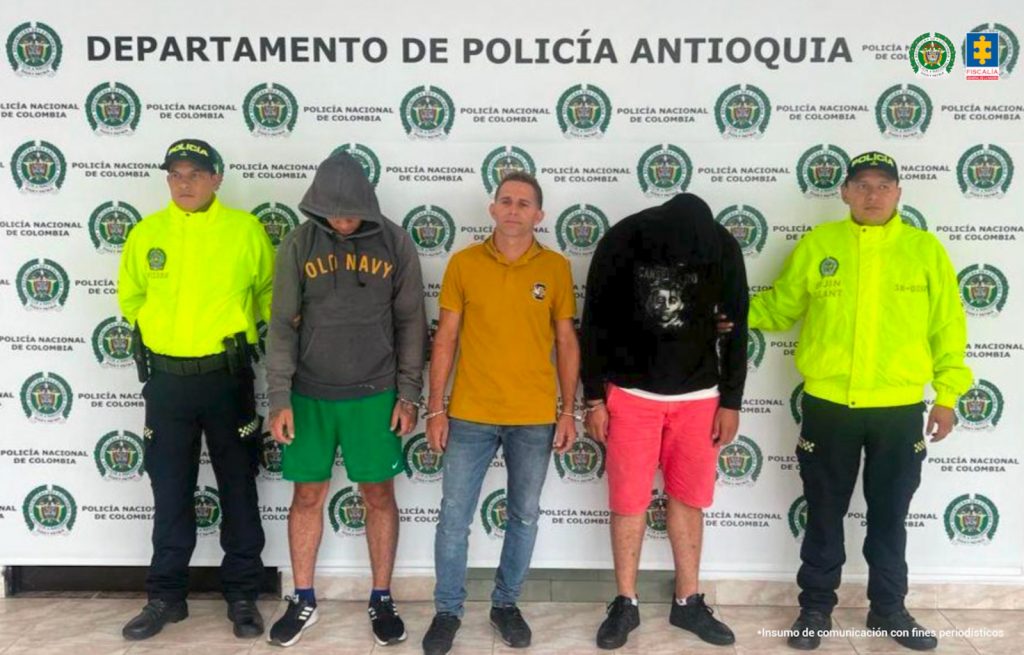 En la fotografía están los 3 capturados con 2 servidores de la Policía Nacional a los lados y un pendón de la institución atrás 