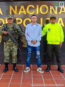 En la fotografía aparece un capturado, junto a personal de Policía Nacional y Fiscalía General de La Nación. En la parte posterior de la imagen se ven banners de Policía Nacional y la Fiscalía General de la Nación.