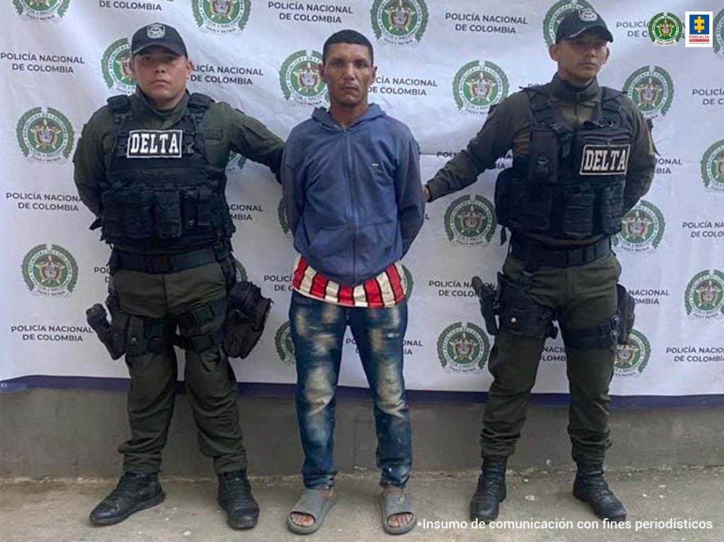 Dos funcionarios de la Policía Nacional custodian al hombre, de 40 años de edad, señalado de llevar en 39 costales más de 300 babillas.