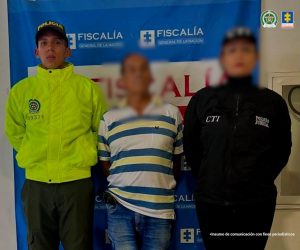 En la fotografía se aprecia de pie y con los brazos atrás a Roberto Ruíz Pérez. Viste camisa de mang corta beage con rayas horizontales gruesas de color verde; jean azul desteñido y zpatos azules con blanco. Al lado izquierdo hay una servidora del CTI de la Fiscalía y al lado derecho un uniformado de la Policía Nacional. Detrás de ellos hay un pendón de la Fiscalía.