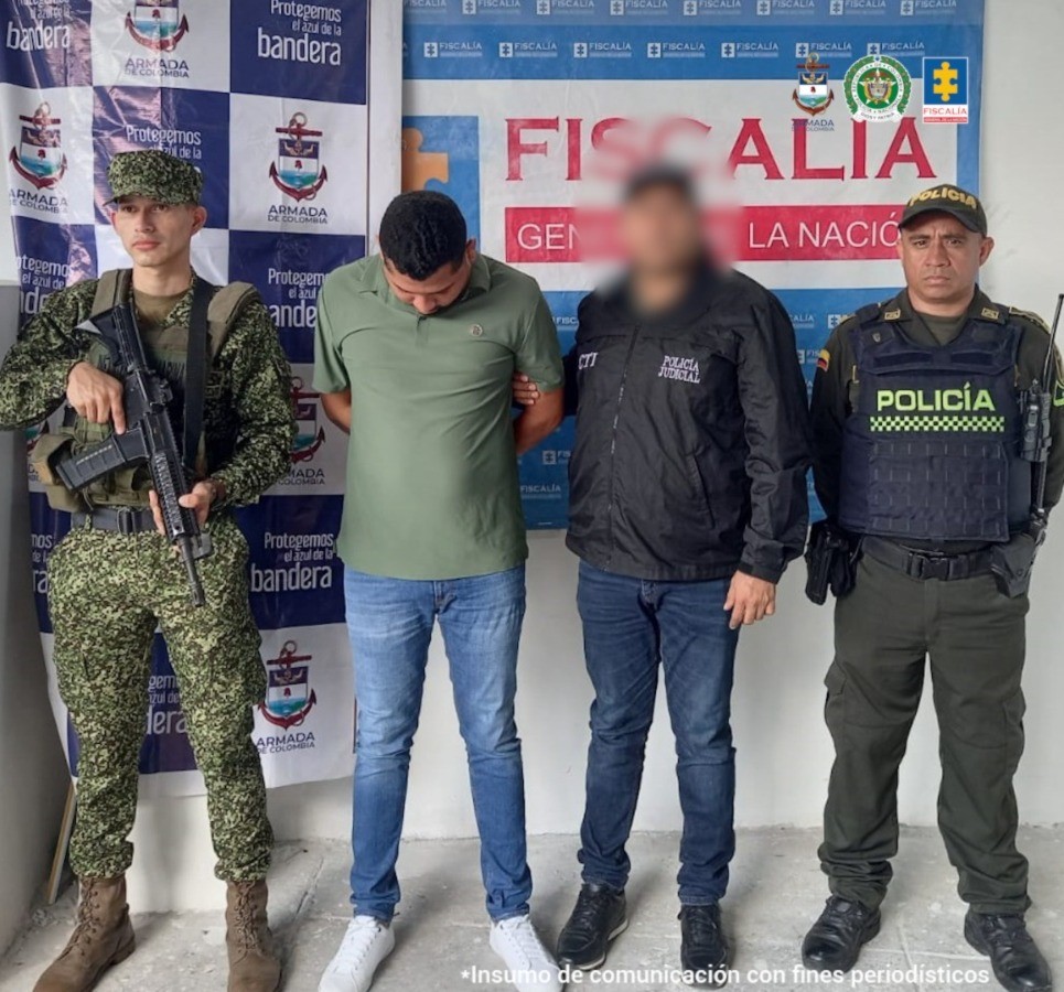 En la imagen aparece una persona de suéter verde, junto a un uniformado del CTI, uno de la Policía y uno de la Armada Nacional.