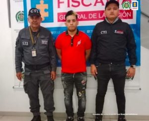 En la fotografía aparece dos investigadores del CTI junto a un hombre capturado. En la parte posterior de la imagen se ve logo de la Policía Nacional y banner de la Fiscalía General de la Nación.