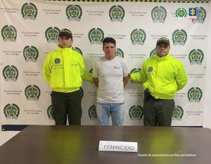 En la fotografía se aprecia de pie, con los brazos atrás a Rubiel de Jesús Gutiérrez Rincón. Viste camiseta blanca de manga corta y jean azul desteñido a la altura de los muslos. A lado y lado de él hay uniformados de la Policía Nacional. Delante de ellos, sobre una superficie marrón hay un letrero que dice: ‘Femincidio’. Detrás de ellos hay un pendón institucional de la Policía.