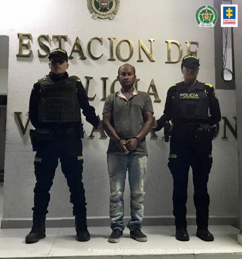 En la fotografía aparece un capturado junto a personal de Policía Nacional. En la parte posterior de la imagen se ven banners de Policía Nacional y Fiscalía General de la Nación. 