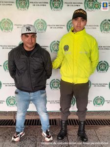En la fotografía aparece un hombre capturado junto a dos agentes de la Policía Nacional. En la parte posterior se ve un banner de la Policía Metropolitana Cali