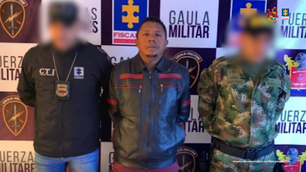 En la imagen aparece una persona de chaqueta negra de cuero, entre dos uniformados del CTI y el Gaula Militar.
