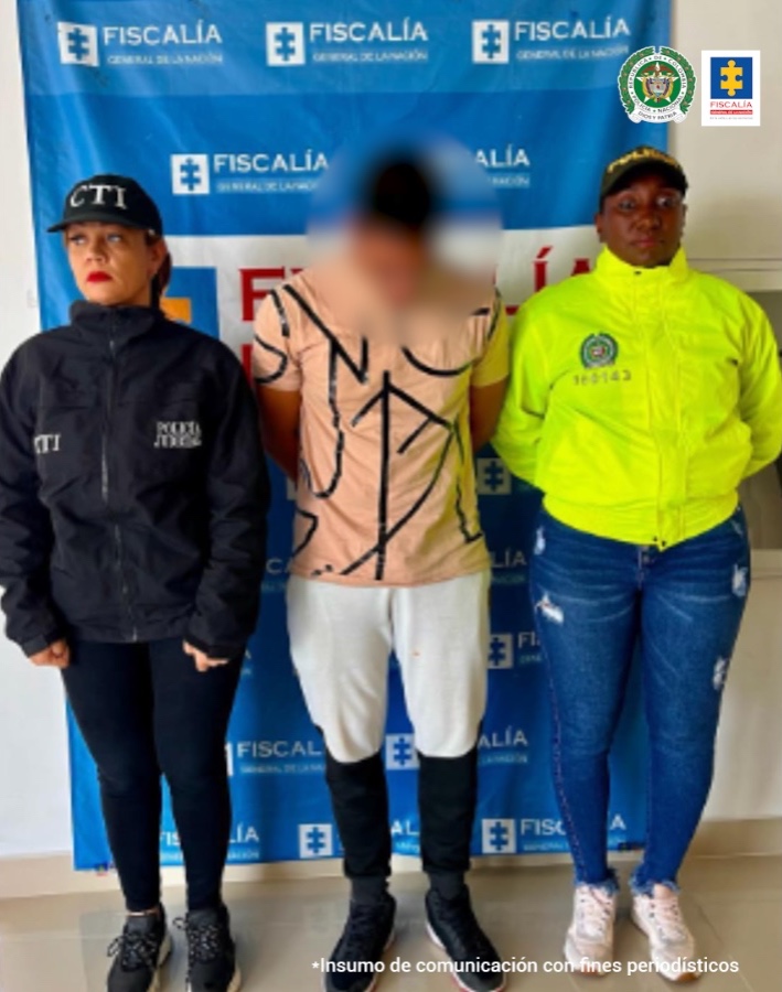 Fiscal Martha Mancera, Martha Mancera, Fiscal Mancera En la fotografía se aprecia de pie y con los brazos atrás a Sergio García Mayor. Viste camisa de manga color salmón claro con estampados negros; pantalón de sudadera blanco de la rodilla hacia arriba y negro de la rodilla hacia abajo; zapatillas negras. Al lado derecho de él hay una servidora del CTI de la Fiscalía y una uniformada de la Policía Nacional. Detrás de ellos hay un pendón institucional de la Fiscalía.