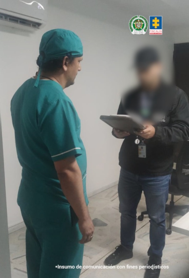 En la imagen se ve a un hombre de uniforme verde menta con una cofia del mismo color en su cabeza. Frente a él un agente del CTI leyendo un documento.