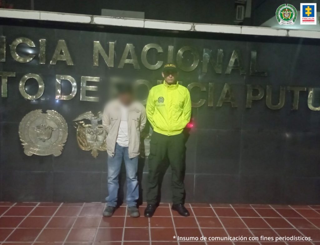 En la fotografía aparece un capturado junto a personal de Policía Nacional. En la parte posterior de la imagen se ven banners de Policía Nacional y Fiscalía General de la Nación.