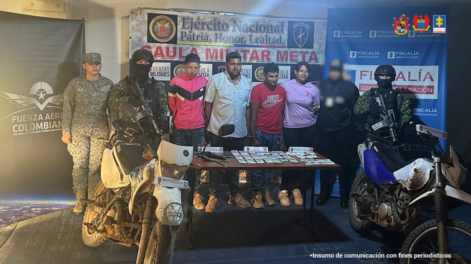 capturados de frente custodiados por investigador del CTI de Fiscalía, militares de ejército y de Fuerza Aérea delante mesa con material incautado, detrás banner de Fiscalía y de Gaula Militar.