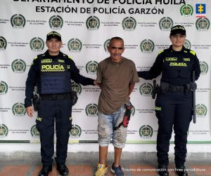 El imputado se encuentra en custodia por dos uniformados de la Policía Nacional. Detrás hay un backing de la Policía.