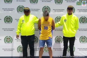 El procesado de camiseta amarilla es custodiado por dos uniformados de la Policía Nacional tras su captura por orden judicial por los delitos de , feminicidio en grado de tentativa, tortura, acceso carnal violento y violencia intrafamiliar, todos en circunstancias de agravación.