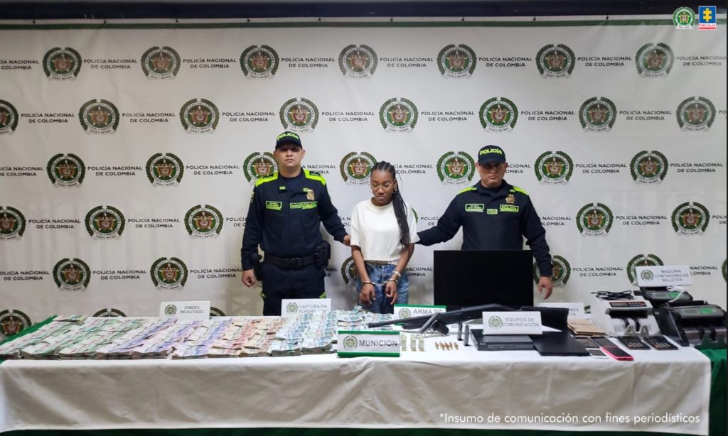 En la imagen está la procesada con dos servidores de la Policía Nacional y una mesa con el dinero y demás elementos incautados