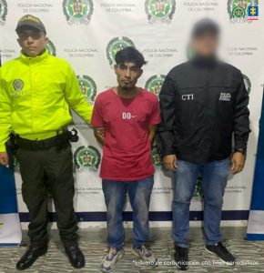 En la fotografía se aprecia de pie y con los brazos atrás a Víctor Hugo Muñoz Herrera, alias Víctor Cabezas. Viste camiseta de manga corta de color rojo, jean azul y zapatillas de color gris con azul. Al lado izquierdo de él hay un servidor del CTI de la Fiscalía y al lado derecho hay un uniformado de la Policía Nacional. Detrás de ellos hay un pendón institucional de la Policía.