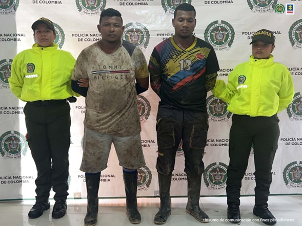 En la fotografía aparecen 2 hombres capturadas, junto a dos uniformados Policía Nacional. En la parte posterior se ve un banner de la Policía Nacional.