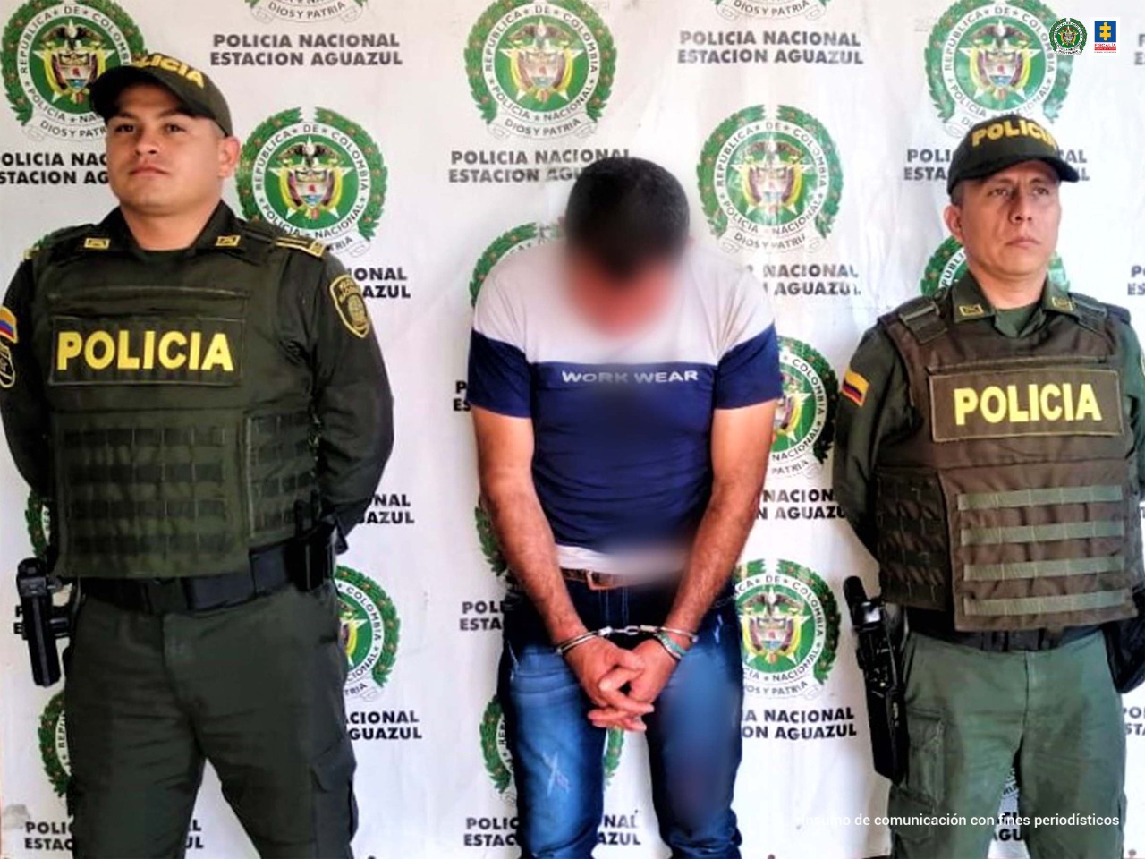 El capturado aparece en la imagen con su rostro agachado, con sus manos esposadas y está custoriado por dos miembros de la policía nacional.