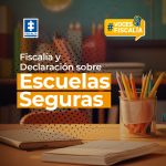 Pieza grafica en donde se ve de fondo una fotografia de un aula de clases en donde se ve un pupitre escolar con unos lapices y cuaderno encima de ella, al fondo de ve una pared con un mapa mundi y unos libros. En letras se puede leer: "Fiscalia y declaracion sobre escuelas seguras" en la parte superior se ve el logo de la Fiscalia y el logo de la sección voces fiscali dentro de un recuadro amarillo
