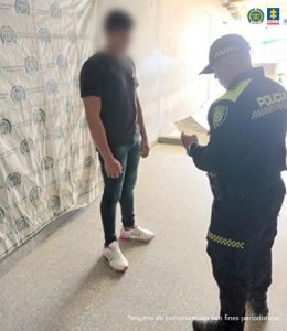 En la imagen aparece una persona con suéter negro frente a un uniformado de la Policía.