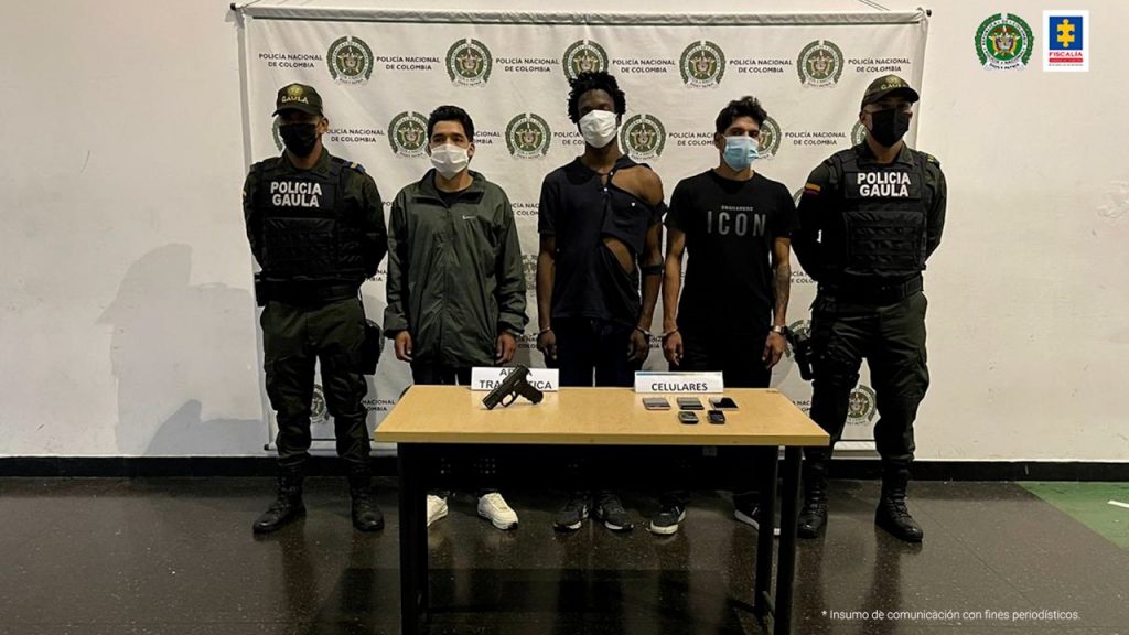 En la imagen se aprecian tres hombres y a su lado aparecen dos uniformados de la policía nacional quienes los custodian. Los tres hombres estarían implicados en los hechos que rodearon el secuestro de una estudiante universitaria. Frente a los tres hombres capturados hay una mesa sobre la que hay una pistola y cinco celulares incautados.
