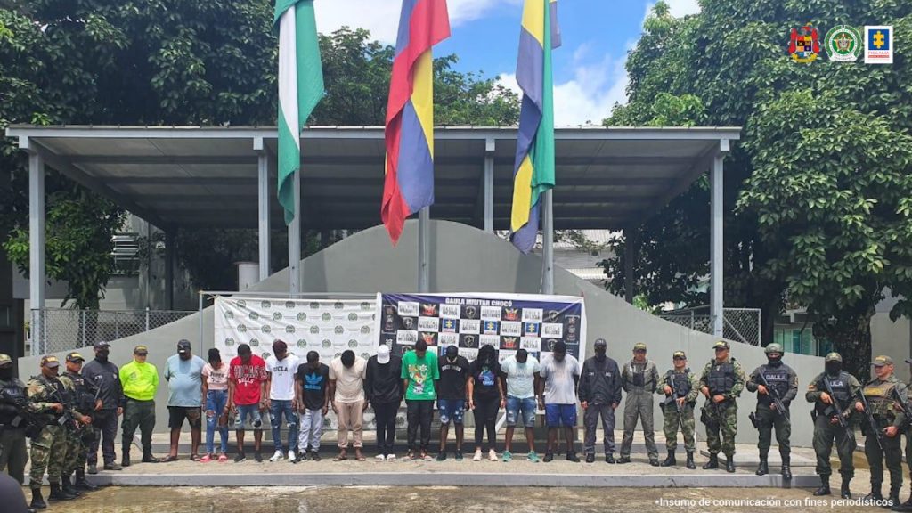 En la fotografía se ve a los 13 capturados durante la Operación Onix. Al fondo se ven los banner con logos de la Fiscalía, Gaula de la Policía y la Policía Naciona.