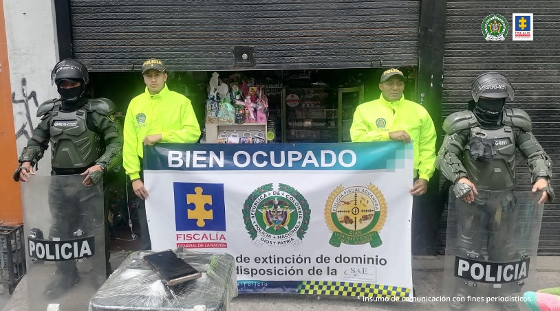 En la imagen se observan uniformados de la Policía Nacional que sostienen un letrero en que se informa que los establecimientos de comercio ubicados a sus espaldas, fueron ocupados con medidas cautelares por haber sido destinados a la comercialización de mercancía de contrabando.