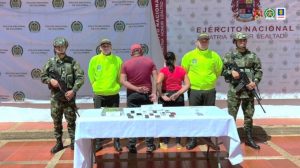 Los capturados aparecen desposados, están de espalda a la cámara y están custodiados por hombres de la Policía y el ejército y en una mesa están los elementos materiales probatorios incautados en el allanamiento.
