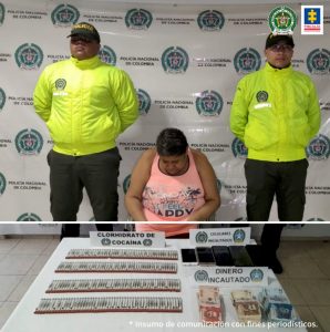 En la fotografía se observa a la detenida junto a dos agentes de la Sijin de la Policía Nariño. En la parte posterior se observa una mesa con clorhidrato de cocaína, dinero en efectivo y 4 teléfonos celulares