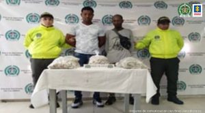 En la fotografía aparecen los dos capturados junto a dos agentes de la Policía Nacional. En la parte posterior se observa una mesa en la que están bolsas cargadas con clorhidrato de cocaína