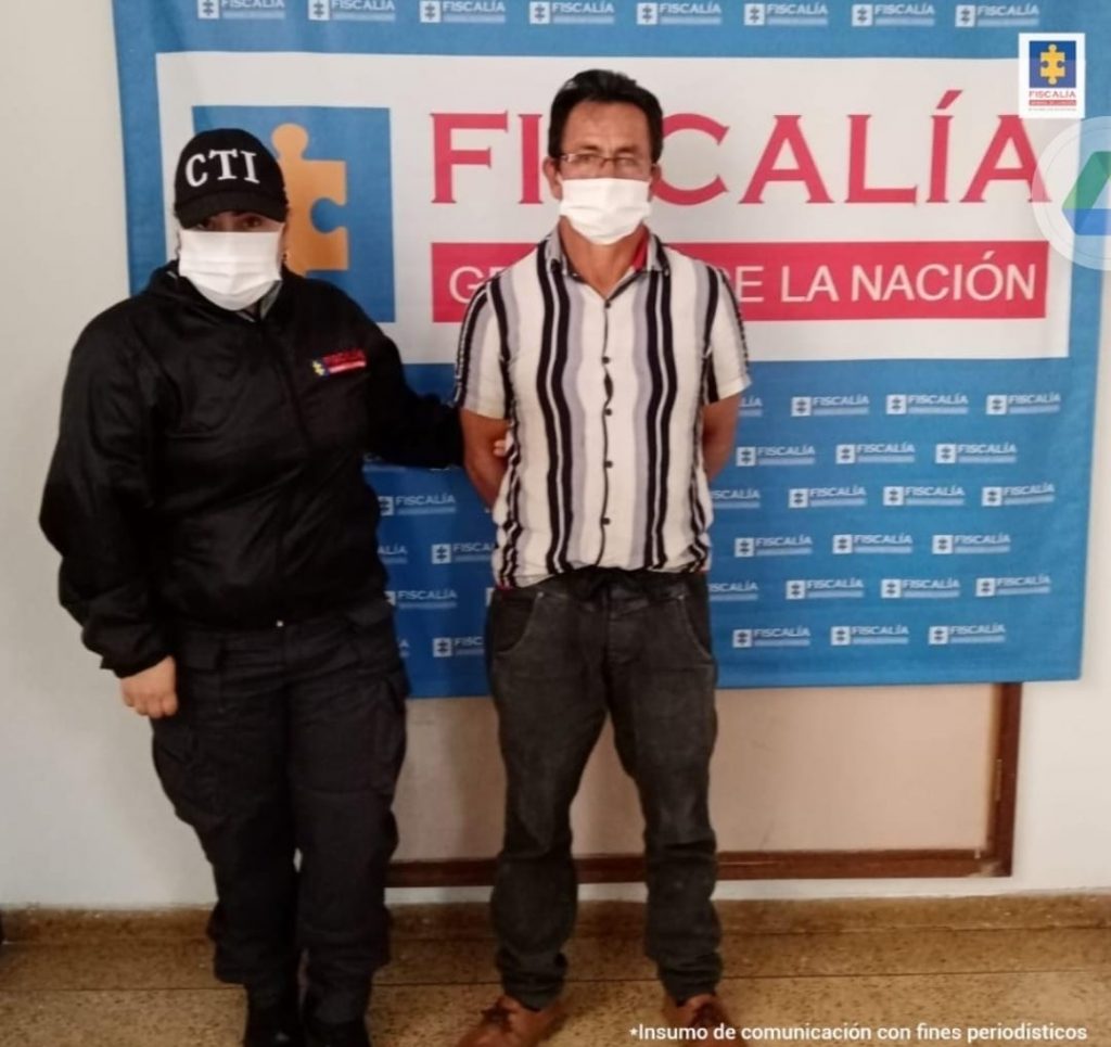 En la fotografía se observa al capturado junto a una servidora del CTI. En la parte superior se observa un banner de la Fiscalía General de la Nación